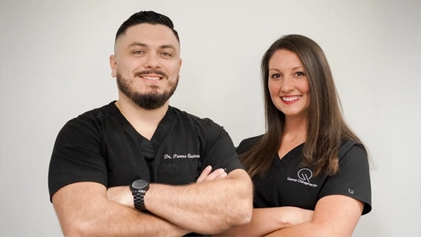 Chiropractor Carrollton TX Pierre Quiroz And Emilee Quiroz HP Pierre Quiroz and Emilee Quiroz smiling while wearing black.